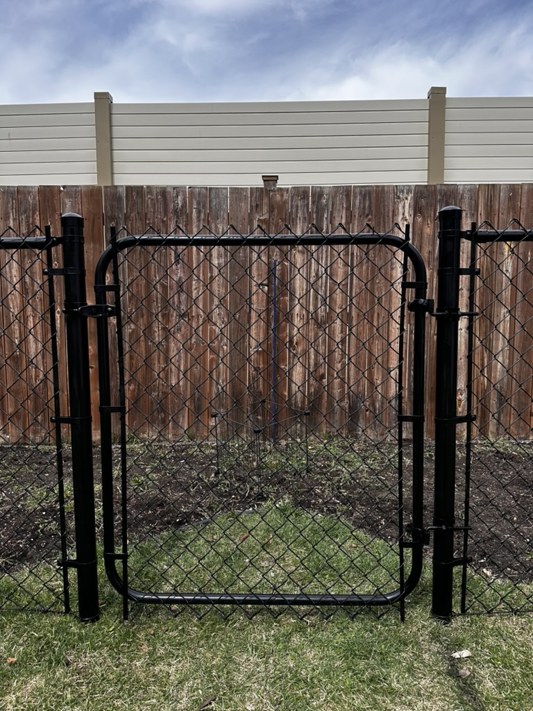 Single-panel black pedestrian gate in a residential fence line