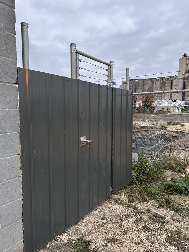 Commercial sheet metal fence gate with barbed wire top